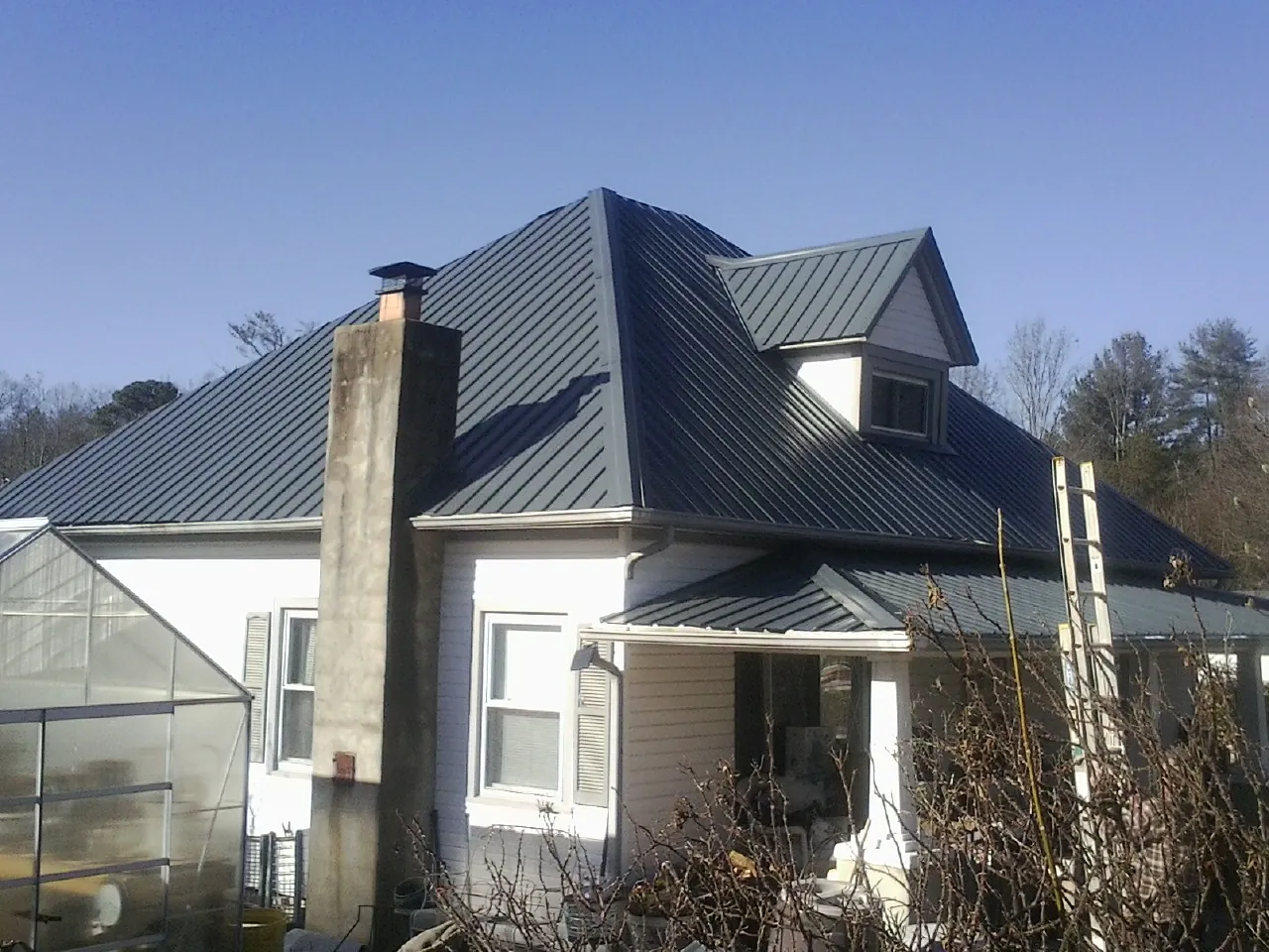 Dark blue standing seam metal roof on a white farmhouse with dormer — Slate & Tile Roof Repair by Roofing Brothers in Bolingbrook