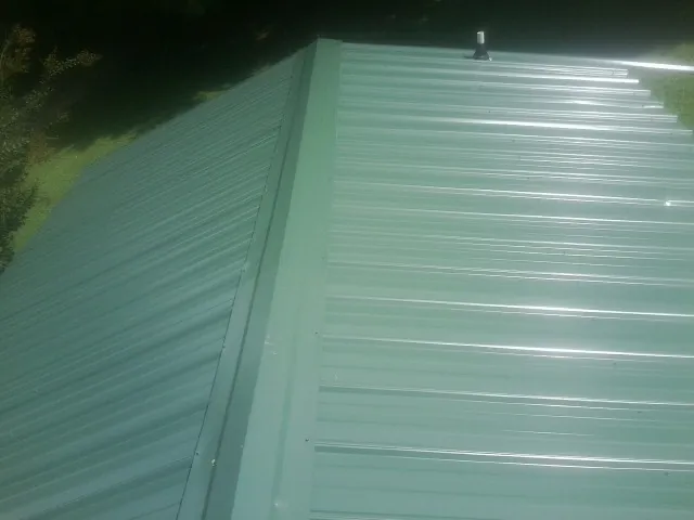 New green metal panels meeting at the ridge of a roof — Flat Roof Repair work by our crew in Bolingbrook
