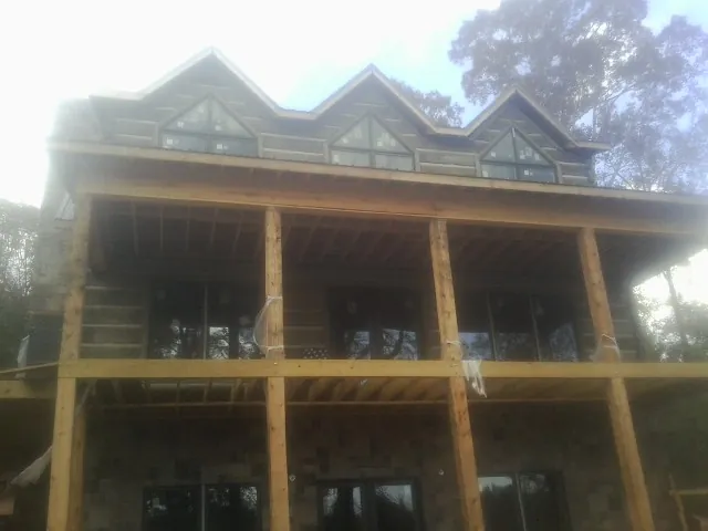 Dormers and porch framing on a large log home under construction — Roof Coating work by our crew in Bolingbrook